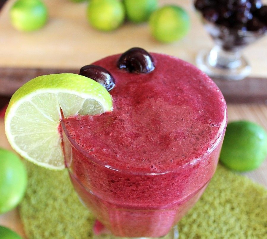 cherry lime slushie in large glass with lime slice