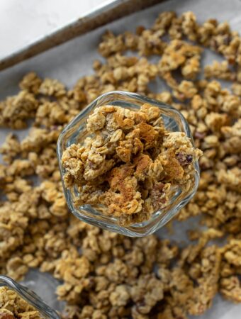overhead view of glass bowl of vegan granola on top of tray of granola