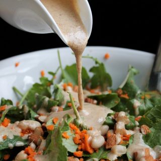 Almond butter dressing pouring over kale salad