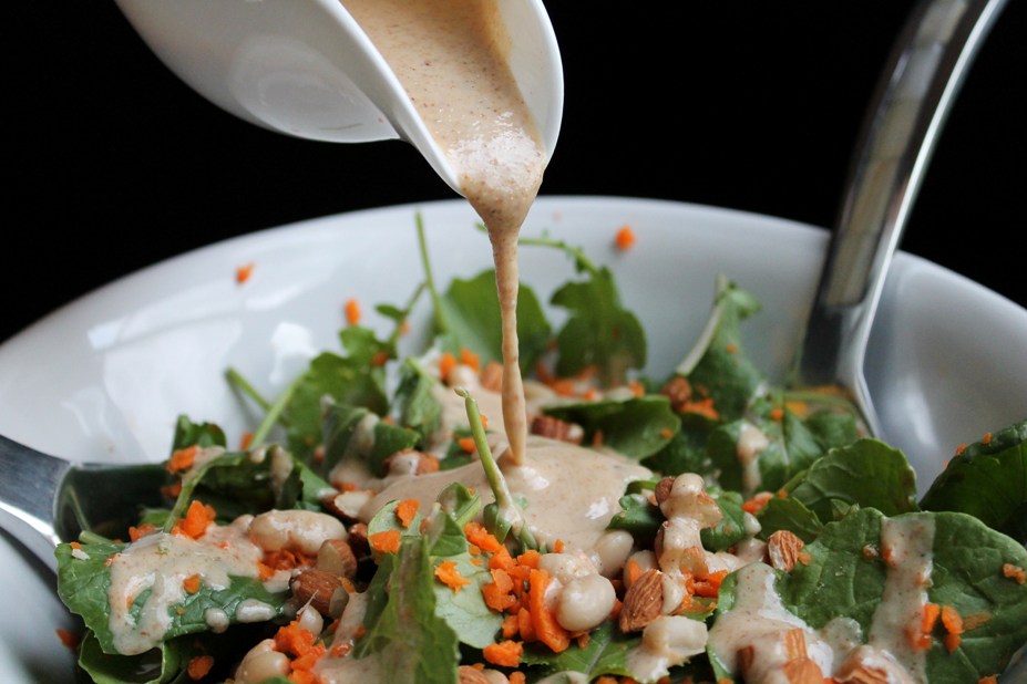 Almond butter dressing pouring over kale salad