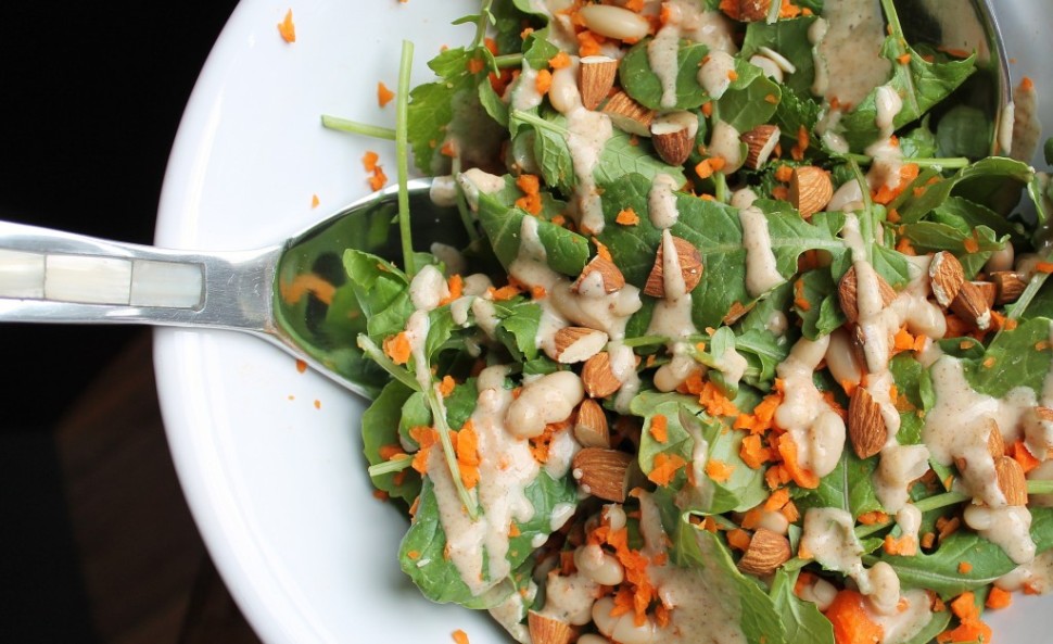 Overhead view of spoon in white bowl of kale salad
