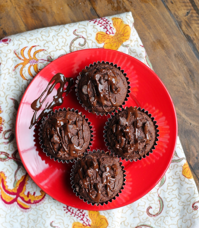 4 muffins on red plate over a flower napkin on wood table