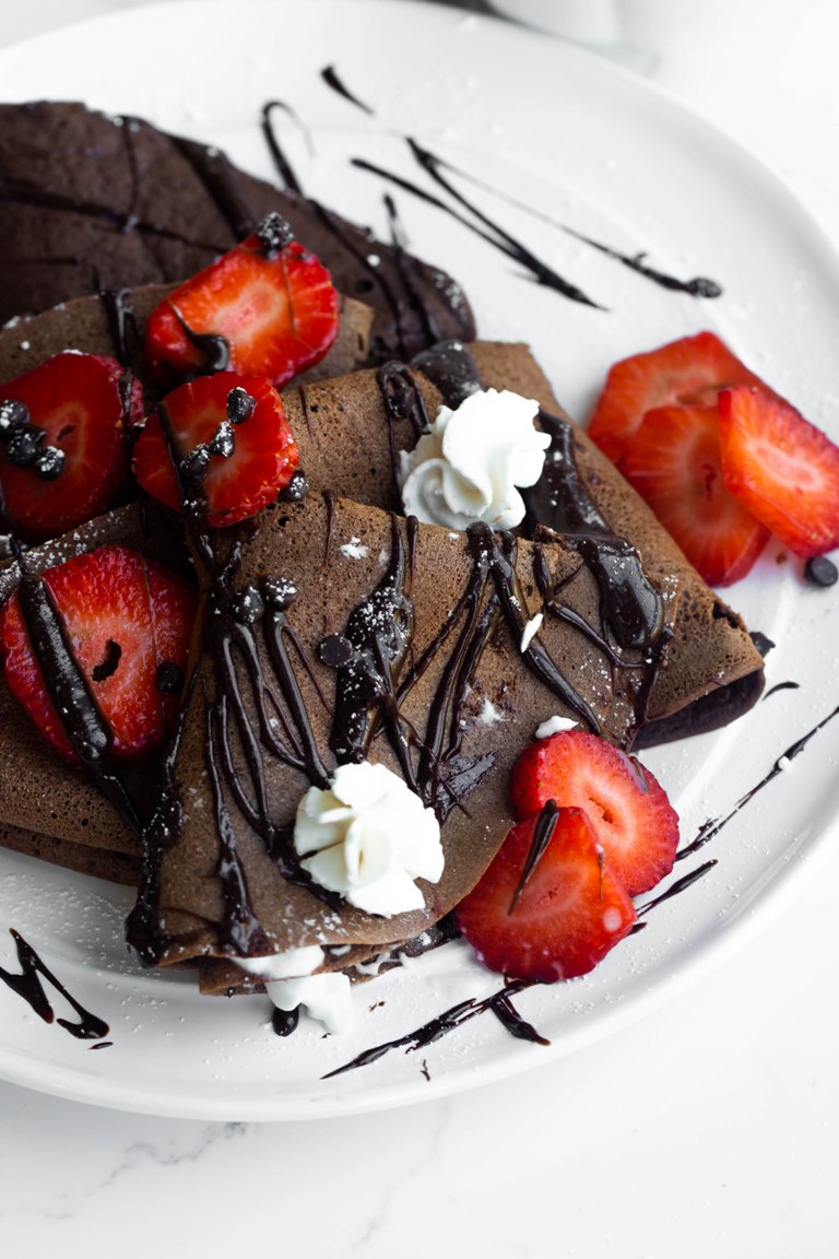 Whipped cream and chocolate sauce on top of chocolate crepes