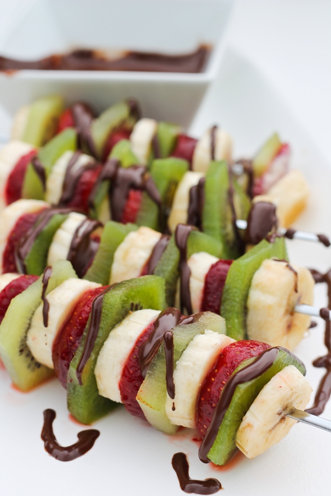 fruit slices on skewers with chocolate drizzled on top
