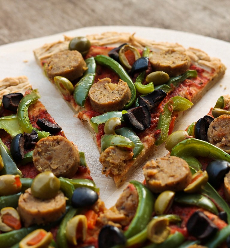 Slice of mashed potato pizza crust with vegan sausage