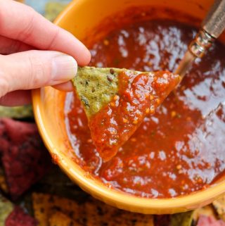 Hand dipping chip into bowl of homemade salsa