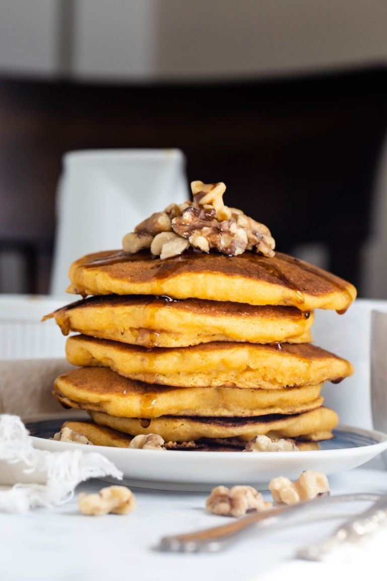 stack of sweet potato pancakes with syrup and walnuts on top
