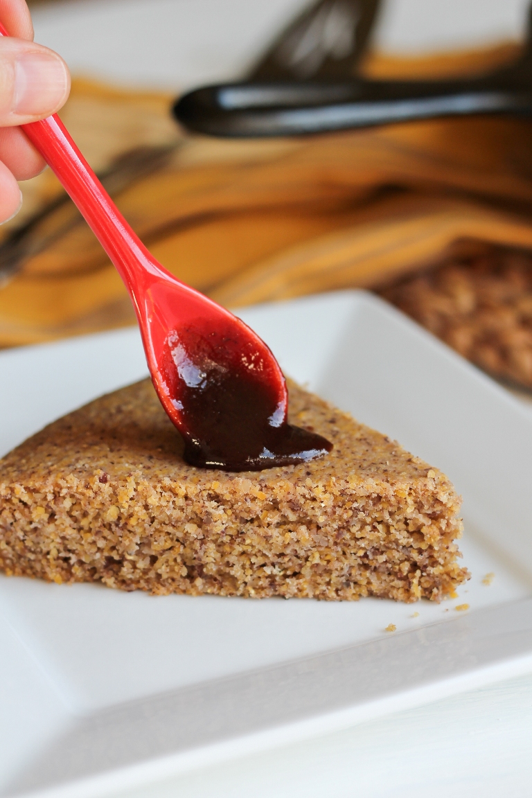 red spoon drizzling barbecue sauce on slice of cornbread