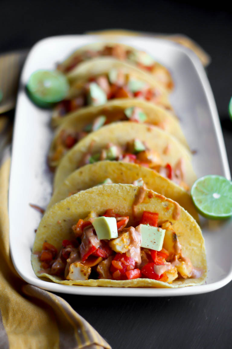 platter of several vegan potato tacos with limes and avocado