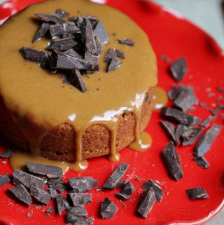 overhead shot of vegan peanut butter glazed cake with dark chocolate pieces on red cake stand