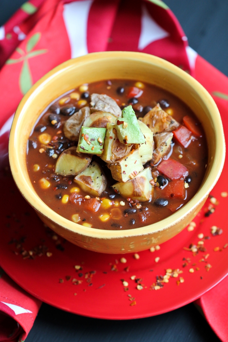 yellow bowl of vegan black bean chili with roasted potatoes and avocado