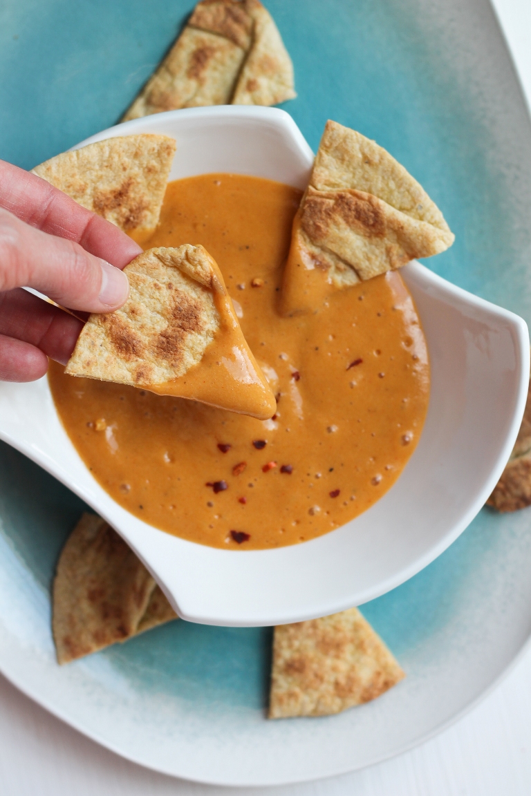 several chips surroungin bowl of cheese sauce
