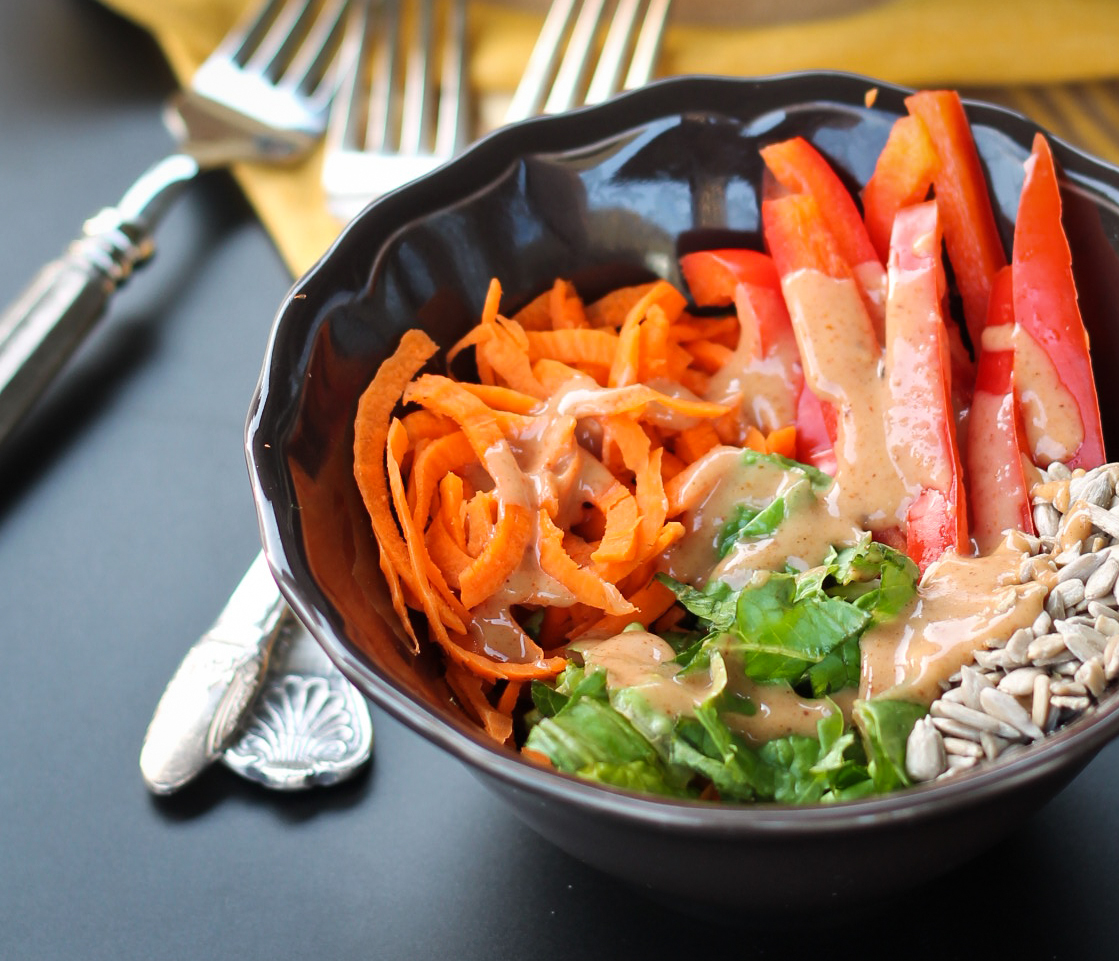 carrot salad in brown bowl with sweet tahini dressing