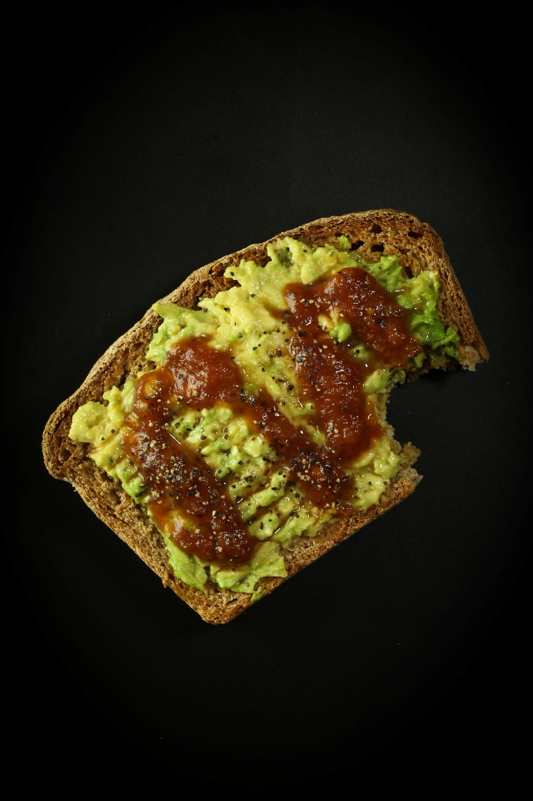 Slice of vegan spelt bread with avocado and bbq sauce on top