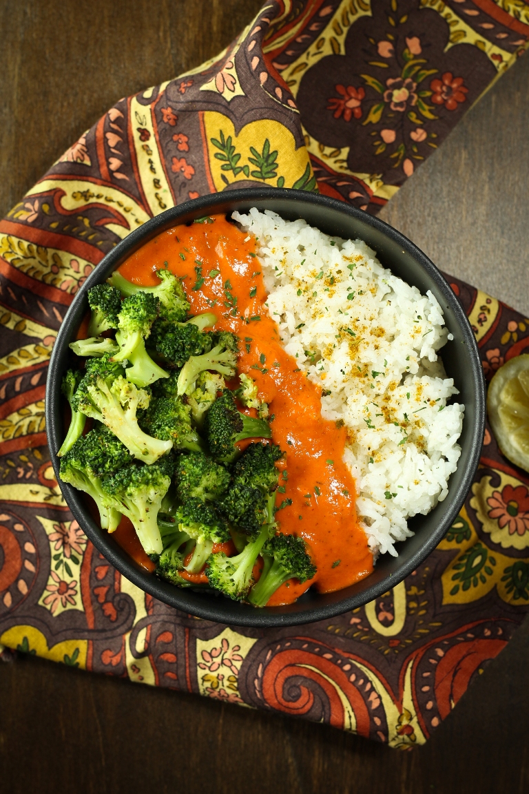 bowl of vegan red pepper curry with rice and broccoli and sauce