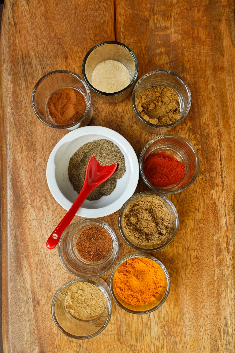 Wooden table with several Indian spices in bowls