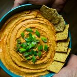 Bowl of Vegan Buffalo hummus with crackers.