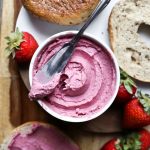 cream cheese in white bowl with knife and bagels alongside