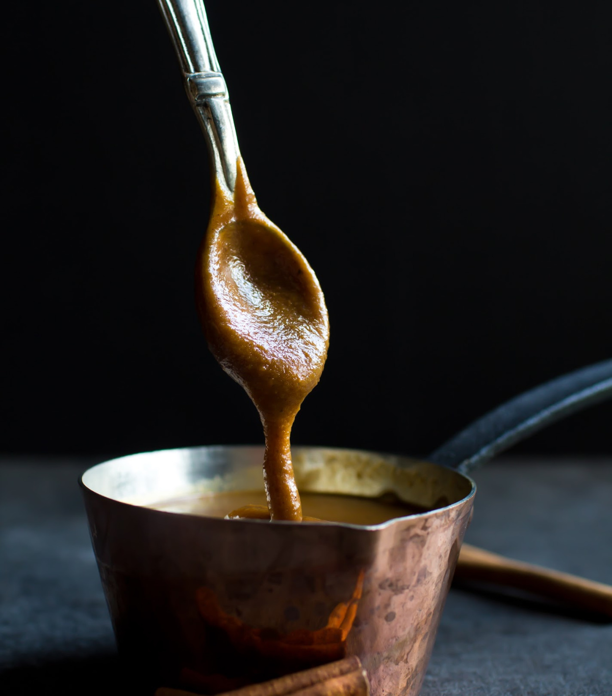 spoon dripping off sweet potato caramel in small pot
