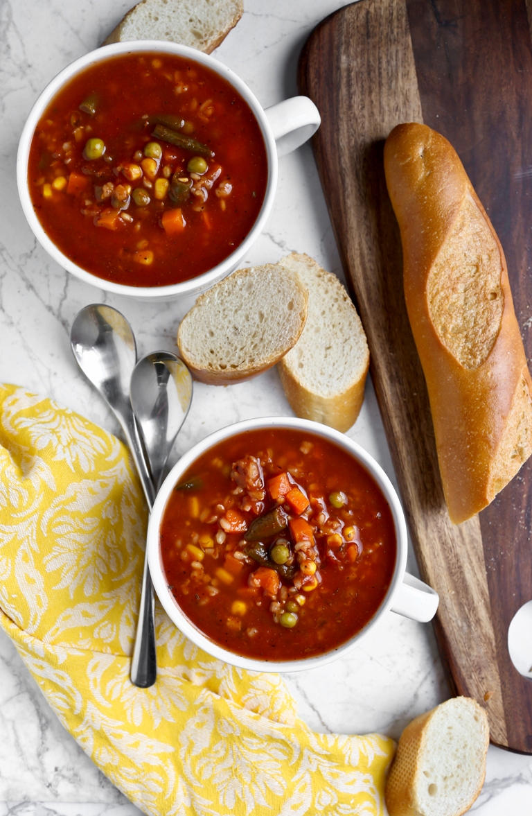 Loaf of bread, 2 bowls of soup and a yellow napkin