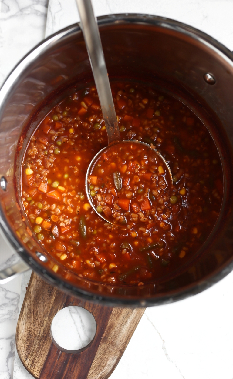 Large stainless steel pot of tomato rice vegetable soup