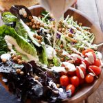 Pitcher pouring vegan ranch dressing over a salad