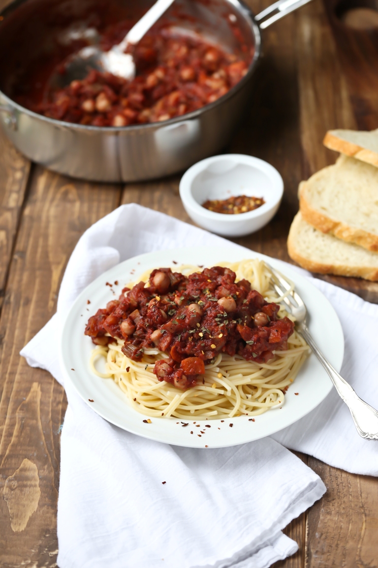 plate of chickpea tomato ragu next to pot and on wood table