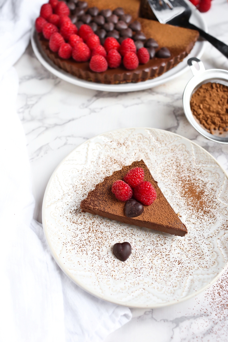 Piece of vegan chocolate sweet potato tart with raspberries