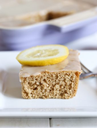 slice of vegan lemon cake with glaze on white plate