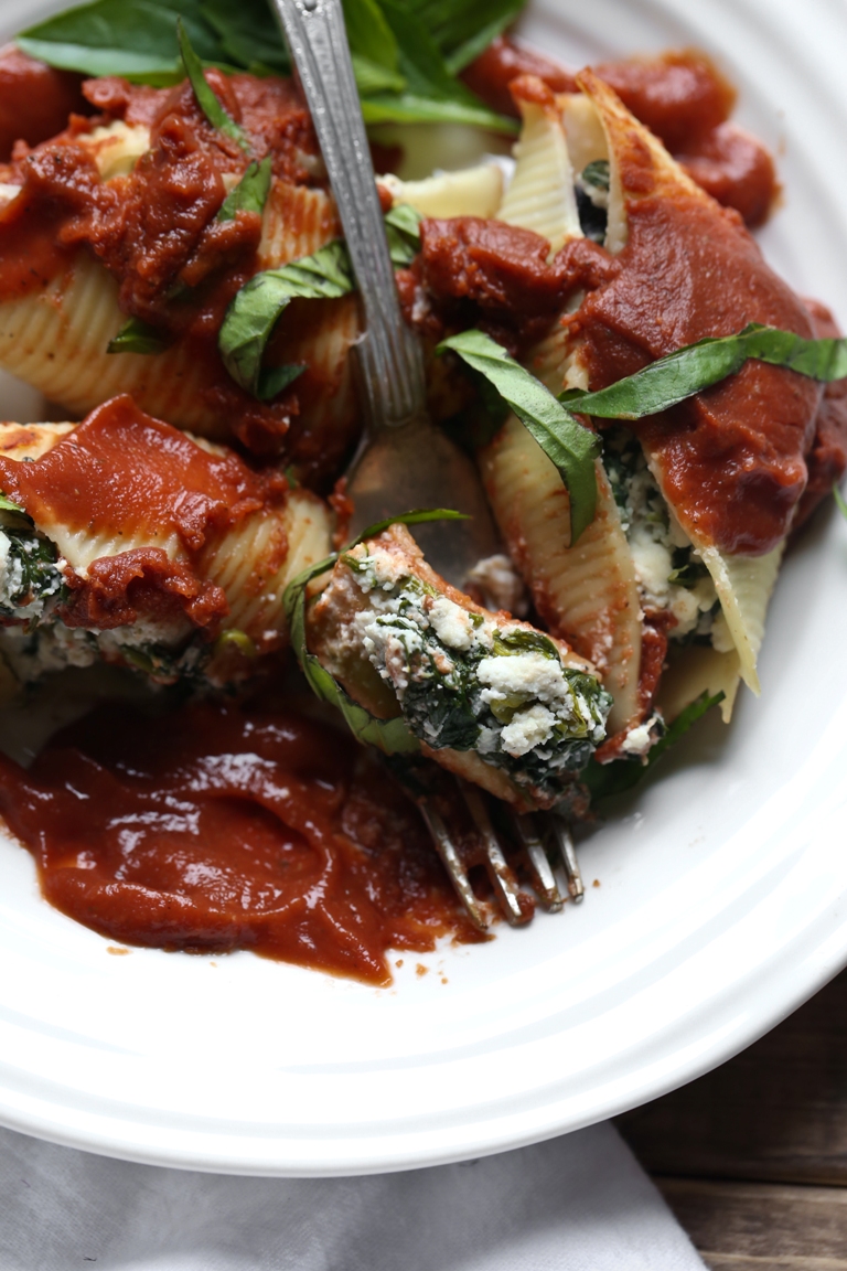 White plate with fork and vegan stuffed ricotta shells and spinach