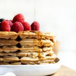 stack of vegan vanilla waffles with syrup pouring above