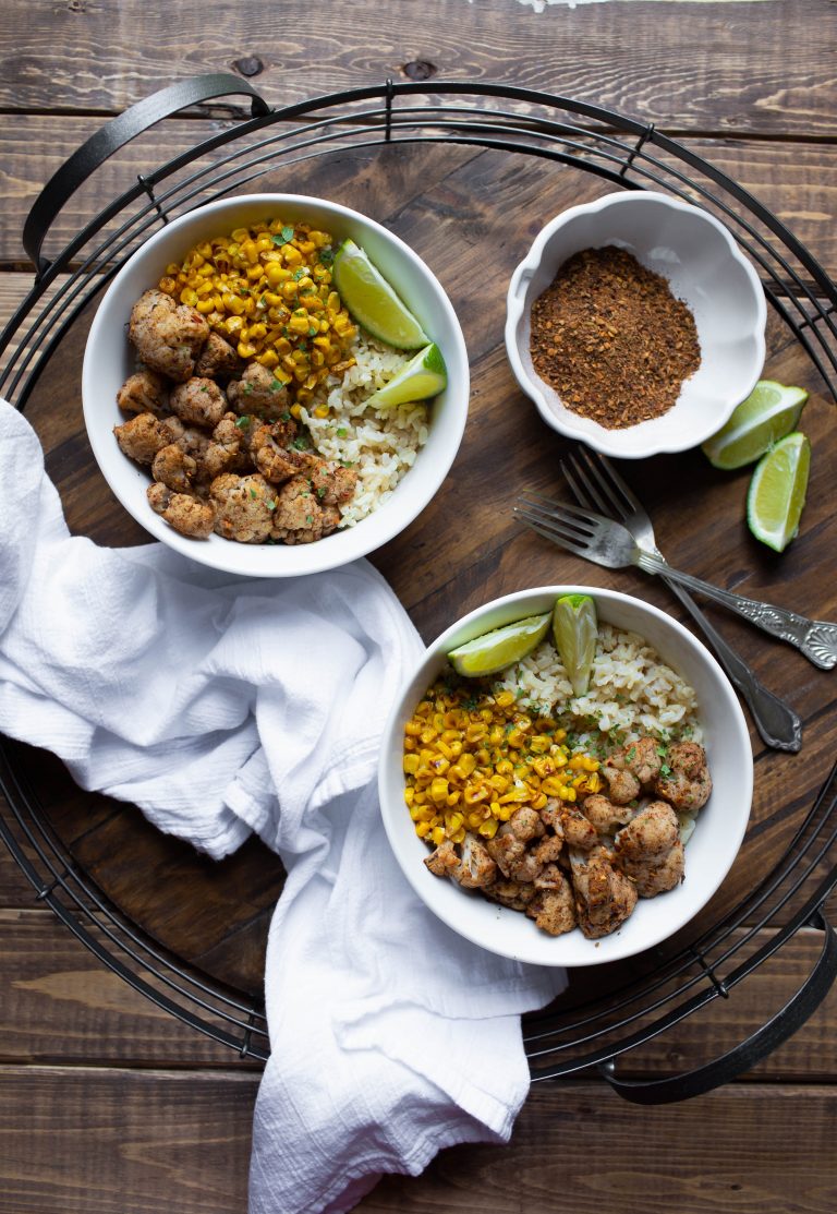 Bowls of jamaican jerk cauliflower white rice and corn