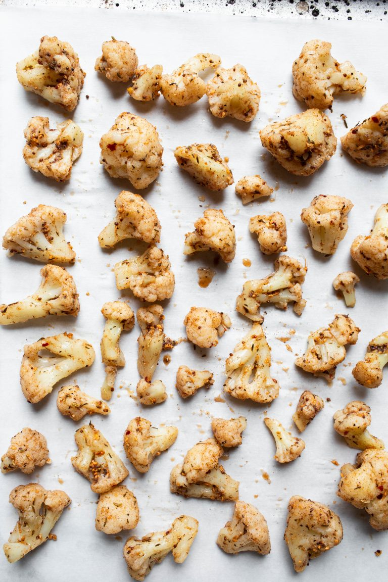 Prebaked pan of Jamaican jerk cauliflower on parchment paper