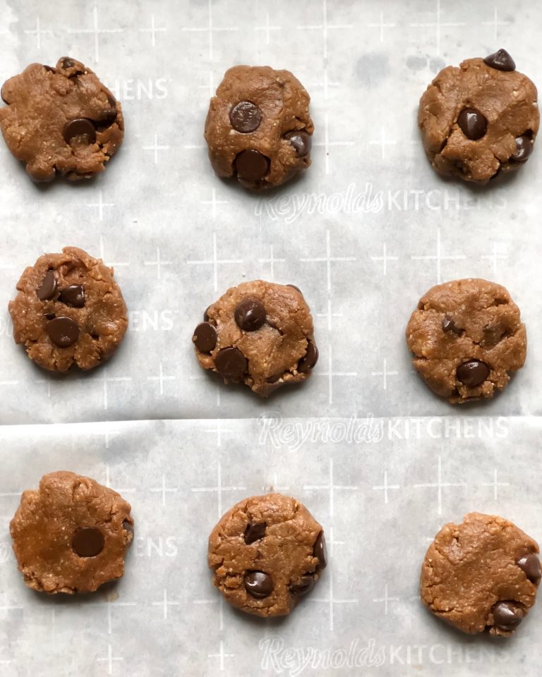 Pre-baked vegan chocolate chip cookies on parchment paper
