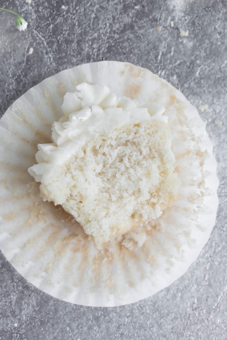 Inside shot of vegan wedding cupcake with white frosting on a paper liner.
