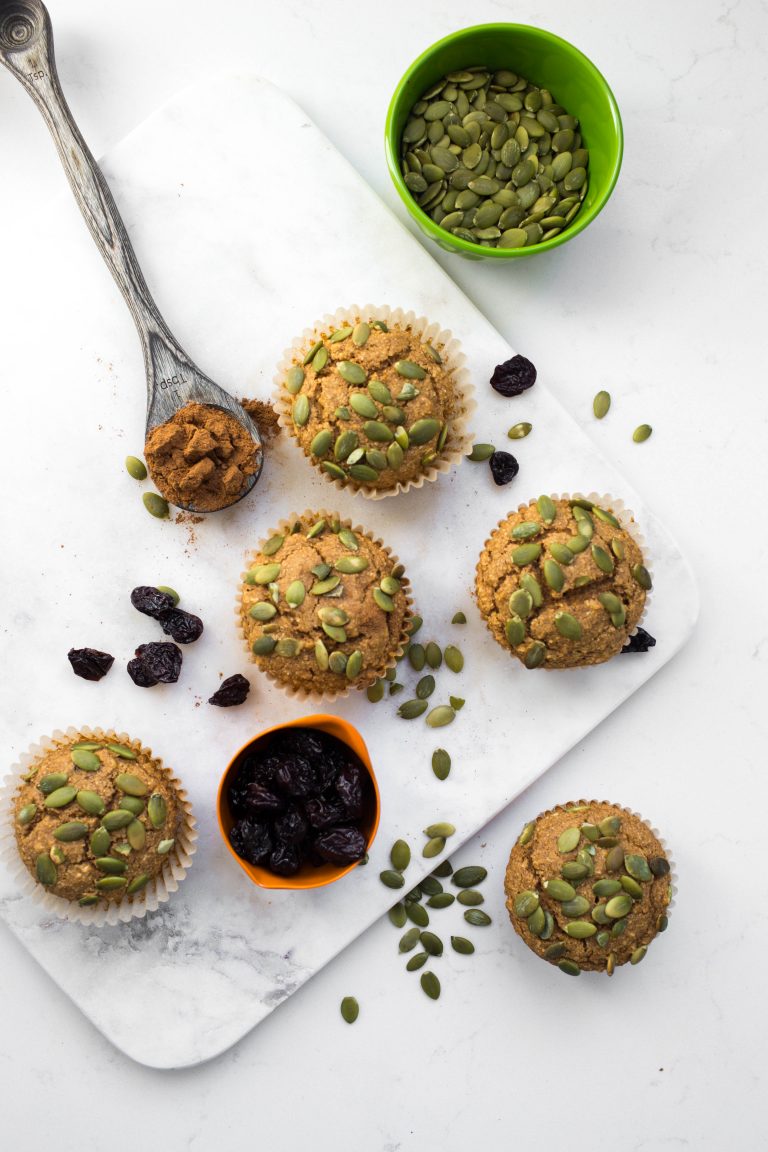 Several vegan pumpkin muffins with pumpkin seeds on top