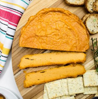 Slices of smoky baked cashew cheese and crackers on platter