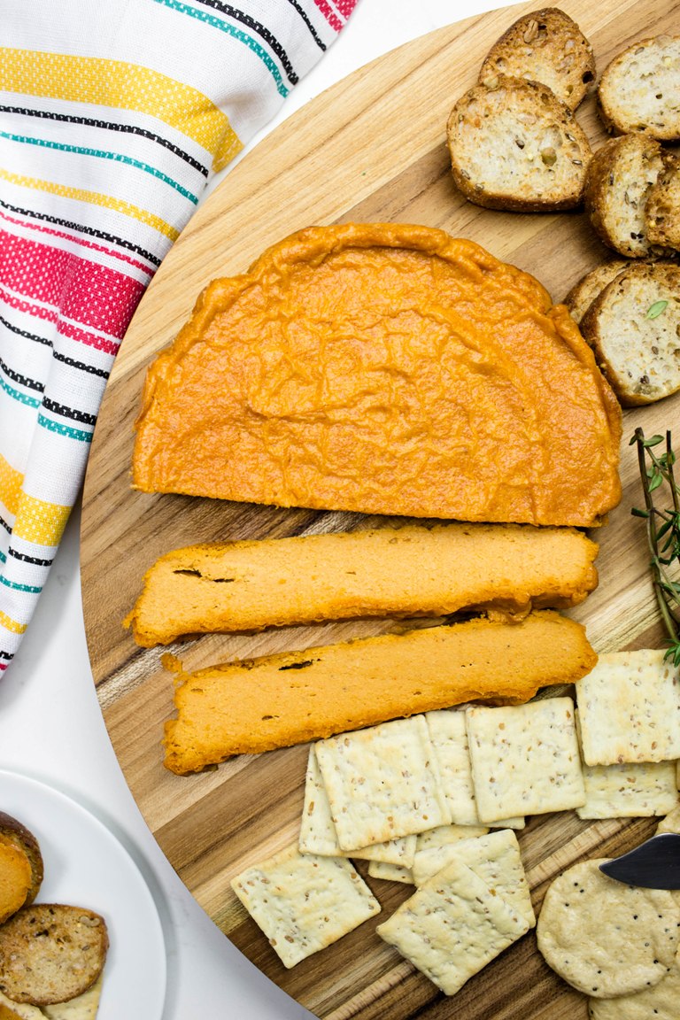 Slices of smoky baked cashew cheese and crackers on platter