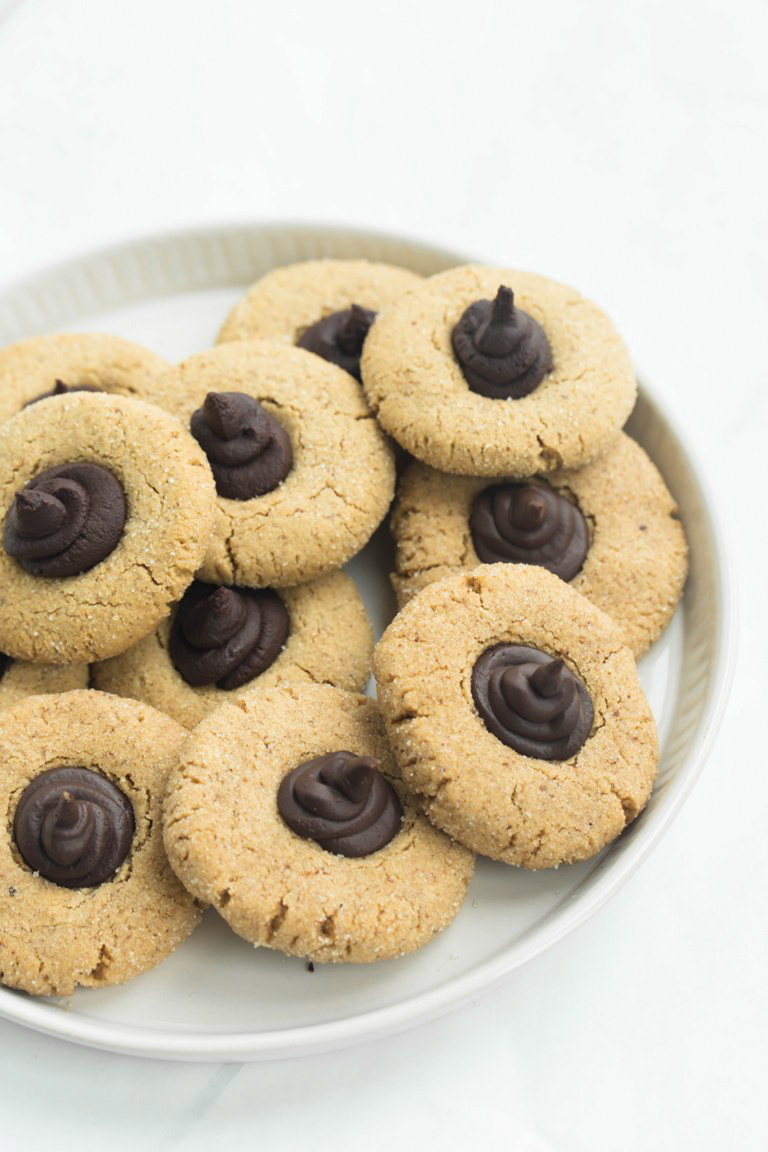 White round plate holding many vegan almond butter blossoms