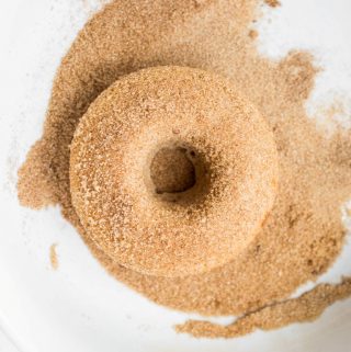 Vegan cinnamon sugar donut in bowl of sugar