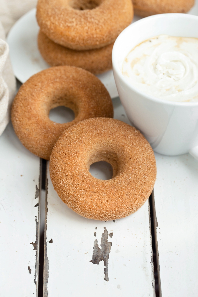 Scattered vegan cinnamon sugar donuts next to coffee