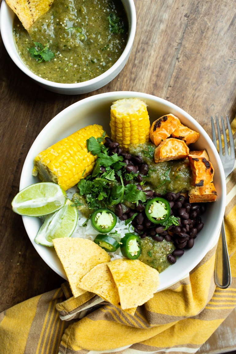 Tomatillo salsa verde in bowl with sweet potatoes rice and beans