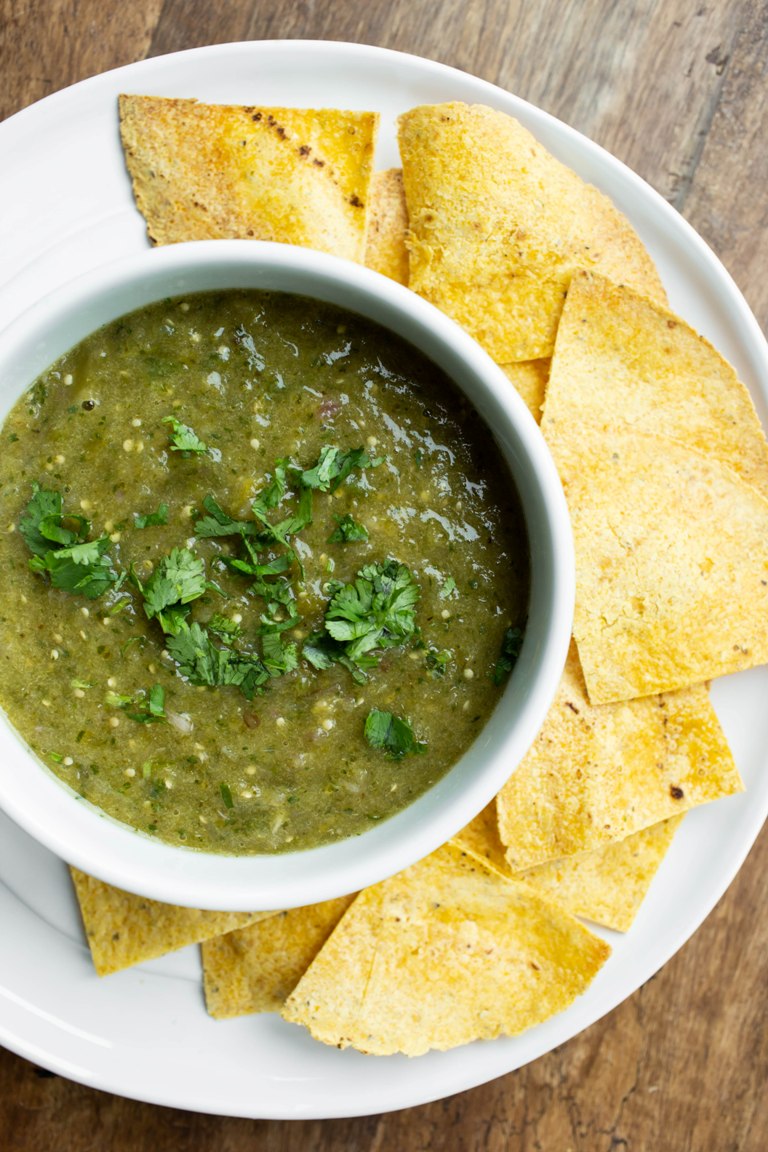 Roasted tomatillo salsa verde in white bowl with chips