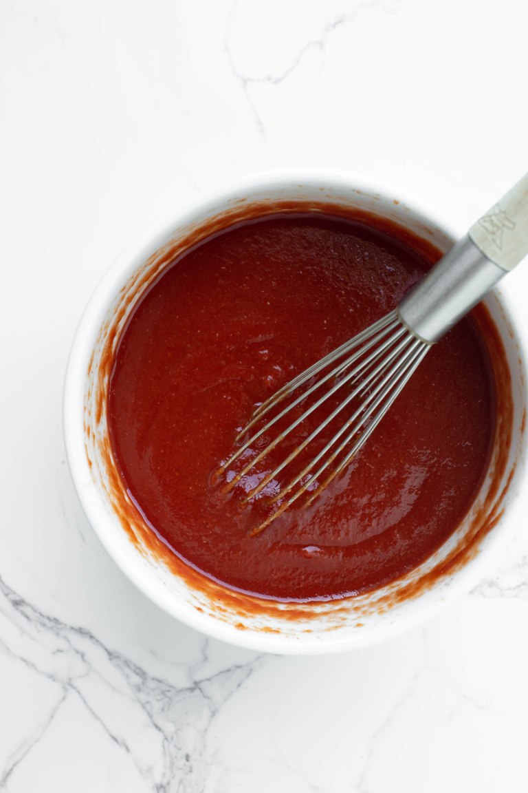 whisking ketchup in white bowl