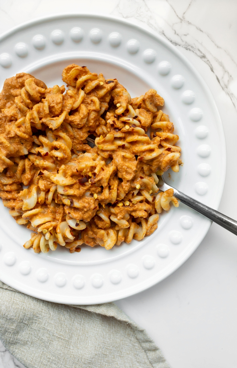romesco sauce mixed in with fusilli pasta on white plate