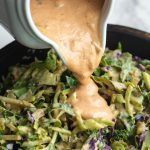 Pitcher pouring over vegan thousand island dressing on salad