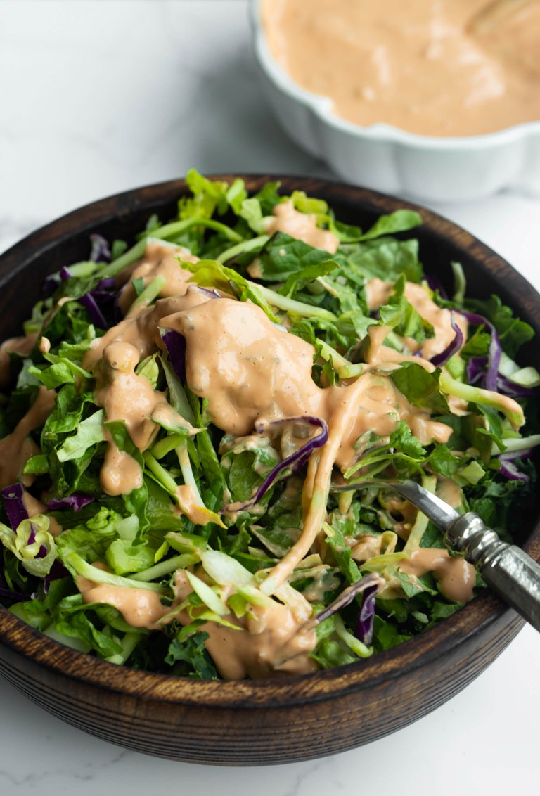 fork sticking in salad with vegan thousand island dressing drizzled on top