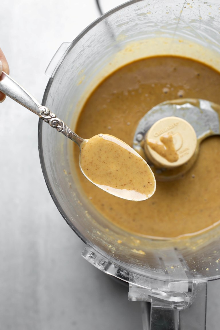 smooth processed walnut butter with a spoon in processor