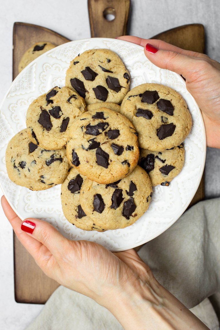 2 hands holding white plate of cashew butter cookies