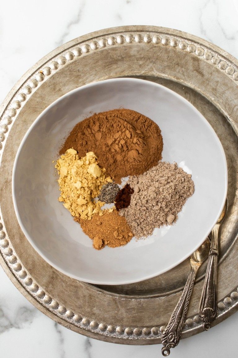 chai spices separated in gray bowl over silver platter